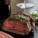 A Warrington Farm Meats baseball cut sirloin steak with herbs on a black surface.