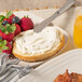 A plate with a bagel and Smithfield Cream Cheese spread with a glass of orange juice on the side.