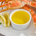 A crab leg dipped in clarified butter on a plate.