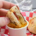 A person dipping bread into a cup of Grandioso garlic sauce.