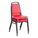 A red stackable chair with a 2-inch padded seat and black metal frame.