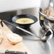 A bowl of soup and a Vollrath Jacob's Pride ladle on a cutting board.