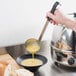 A person using a Vollrath stainless steel ladle to pour soup into a bowl.