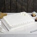 A rectangular white cake displayed on a white cake board.