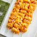 A plate of food with Cornerstone shredded cheddar cheese and bacon skewers on a table.