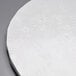 A white Enjay round cake drum with a fold-under edge decorated with leaves.