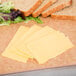 A Cooper Cheese solid block with slices on a cutting board with bread.