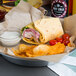 A plate of food with a Mission jalapeno cheese tortilla wrap, chips, and salsa.