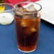 A Carlisle clear polycarbonate tumbler filled with iced tea on a table.