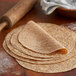 A stack of Mission whole wheat tortillas on a wooden table.