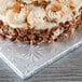 A frosted cake on a silver Enjay square cake drum on a table in a bakery display.