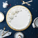 A white cake with white frosting on a gold Enjay cake board on a blue table.