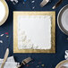 A white square cake on a gold square cake board.