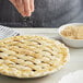 A person sprinkling Golden Barrel raw sugar on a pie.