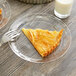 A slice of pie on a WNA Comet clear plastic plate with a fork next to a glass of milk.