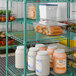 A green wire shelf unit with multiple tiers, used for storage in commercial kitchens or pantries.