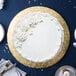 A white cake with white frosting and flowers on a gold Enjay cake board on a table.