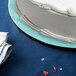 A white cake on a blue Enjay cake drum on a table.