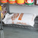 A metal shelf with a plastic container of Golden Barrel light brown sugar with a white cap.