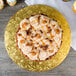 A cake with caramel frosting and pecans on a gold Enjay cake drum.