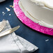 A close-up of a white cake with a pink rim on a pink Enjay round cake board.