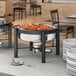 A buffet with a Acopa wrought iron chafer stand and plates of food on a table.