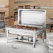 A Choice stainless steel chafer stand on a buffet table with food inside.