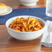 A bowl of pasta with meat sauce and cheese served in an Acopa bright white porcelain bowl.