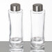 A couple of glass containers with silver lids containing salt and pepper.