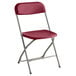 A red Lancaster Table & Seating folding chair with a metal frame.