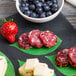 A plate of cheese, fruit, and meat on American Metalcraft Leaf Cheese Paper on a table.