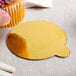 A finger holding a cupcake with sprinkles on a gold and black Enjay dessert board.