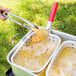 A person using tongs to fry chicken in a Backyard Pro fry pot.