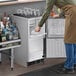 A man standing in front of an undercounter ice machine.