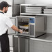 A man using a Beverage-Air countertop blast chiller in a professional kitchen.