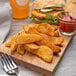 Lamb Weston Seasoned Wedge Cut fries on a wooden cutting board with a burger and a side of red sauce.