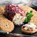 A plate with cheese, crackers, and cookies with a Fresh Gourmet Infused Dried Cranberry on top.