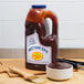 A bottle of Sweet Baby Ray's barbecue sauce on a table with a bowl of barbecue sauce.