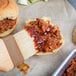 A close up of a bbq pulled pork sandwich with Sweet Baby Ray's BBQ sauce.