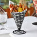 A black Tablecraft wire cone basket with food on a table.