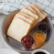 A plate with a sliced European Bakers white bread loaf and jam on a table.