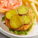 A burger with B&amp;G kosher dill pickle chips and fries on a plate.