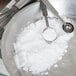 Measuring spoons with white powder in a bowl.