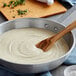 A pan of Stouffer's Alfredo Sauce with a wooden spoon in it.