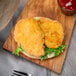 A Brakebush chicken breast slider with lettuce on a wooden board.