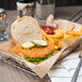 A basket with a breaded chicken sandwich and fries with a bowl of ketchup.