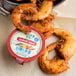 A bowl of shrimp with Ken's Cocktail Sauce dipping cups on a counter.