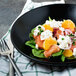 A bowl of salad with orange slices and crumbled goat cheese.