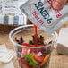 A hand pouring Ken's Fat-Free Raspberry Vinaigrette from a packet onto a salad.