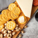 A BelGioioso Parmesan cheese wedge on a wooden board with crackers.